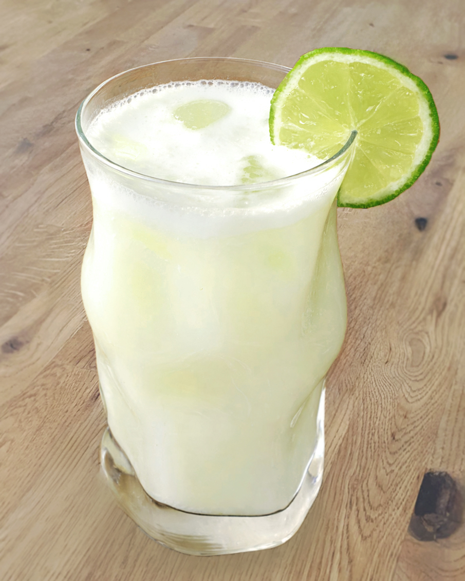Glas mit brasilianischer Limonade, gefüllt mit einer heller, sprudelnder Flüssigkeit und einer Limettenscheibe als Garnitur.