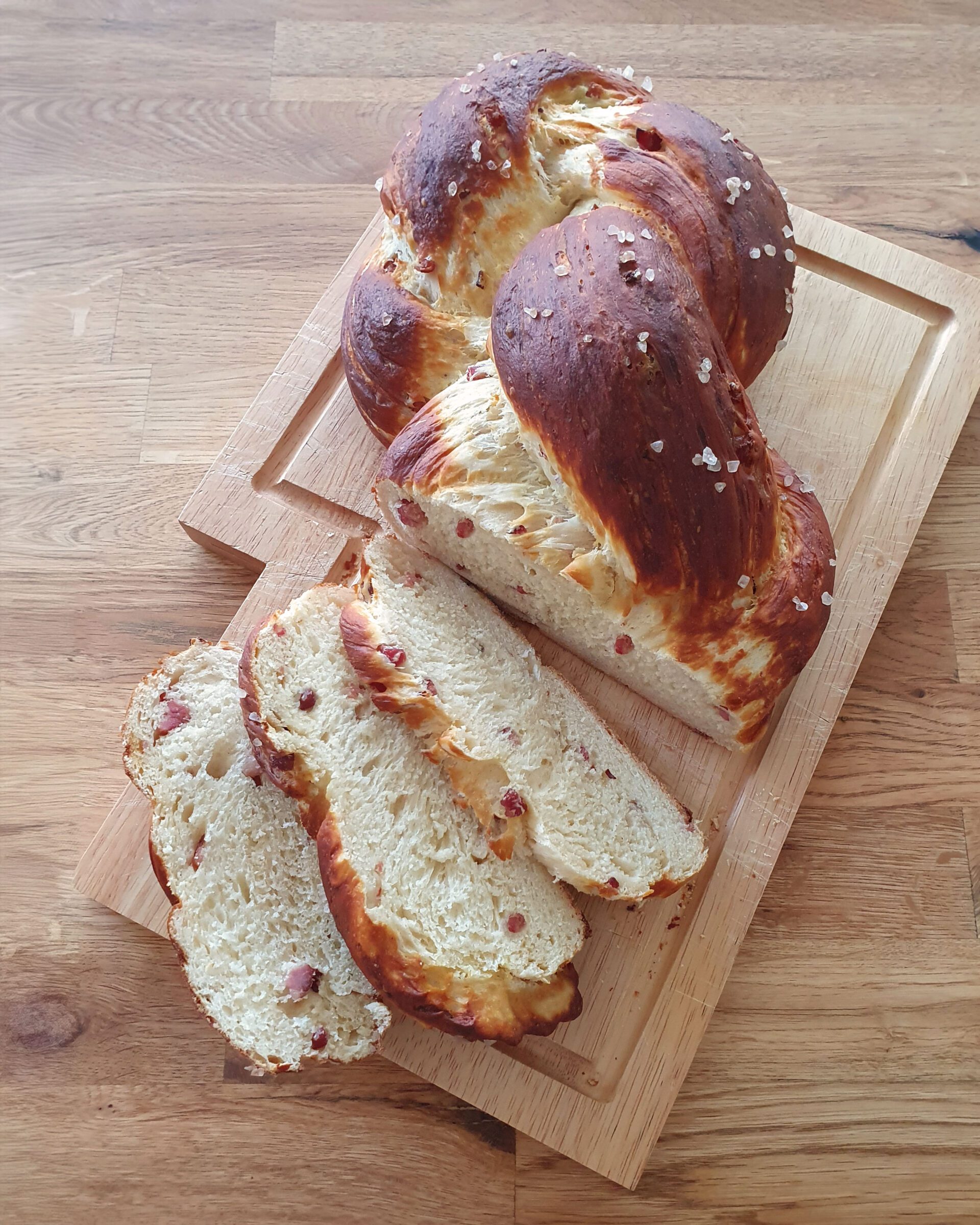 Herzhafter Laugenzopf mit würzigem Speck: braune, glänzende Kruste mit grobem Meersalz, innen luftig mit sichtbaren Speckwürfeln.