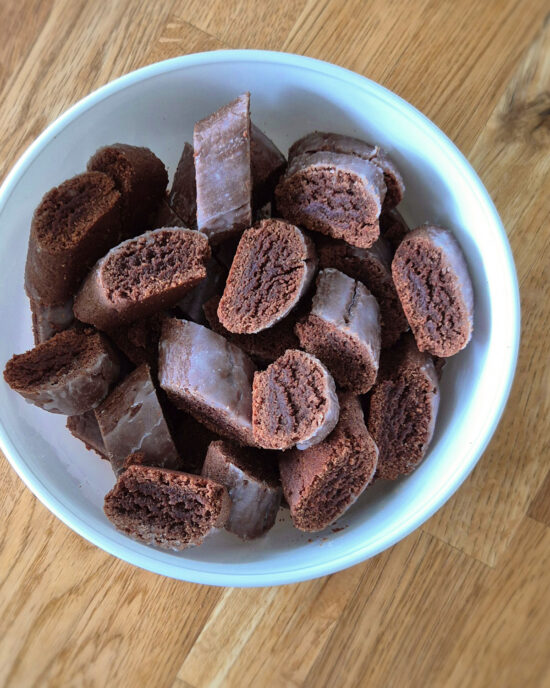 In einer weissen Schüssel liegt in Scheiben geschnittenes Alpenbrot, ein weiches, kakaohaltiges Gewürzgebäck mit glänzender Glasur.